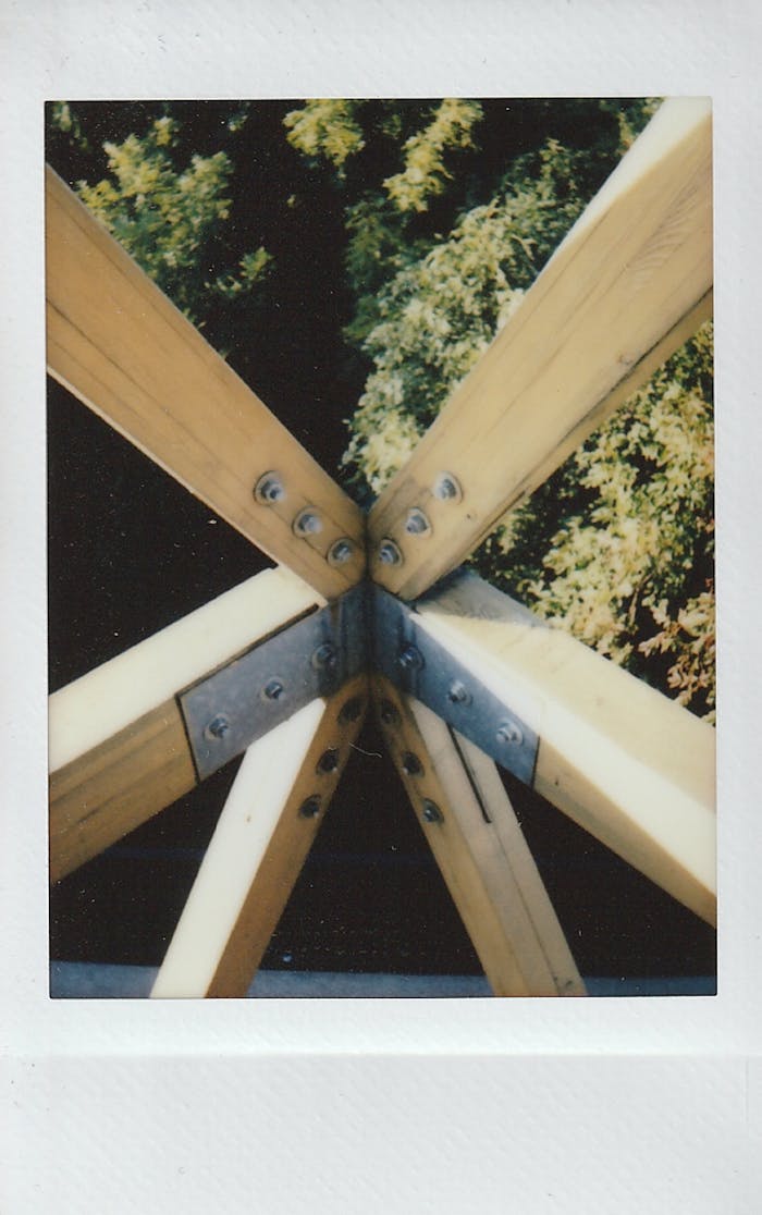 Close-up of wooden beams with metal bolts in a natural outdoor setting.