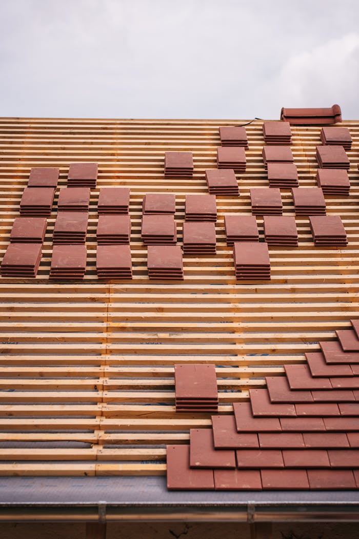Entreprise View of a roof under construction with red tiles and wooden lattice framework, showcasing modern architecture techniques.
