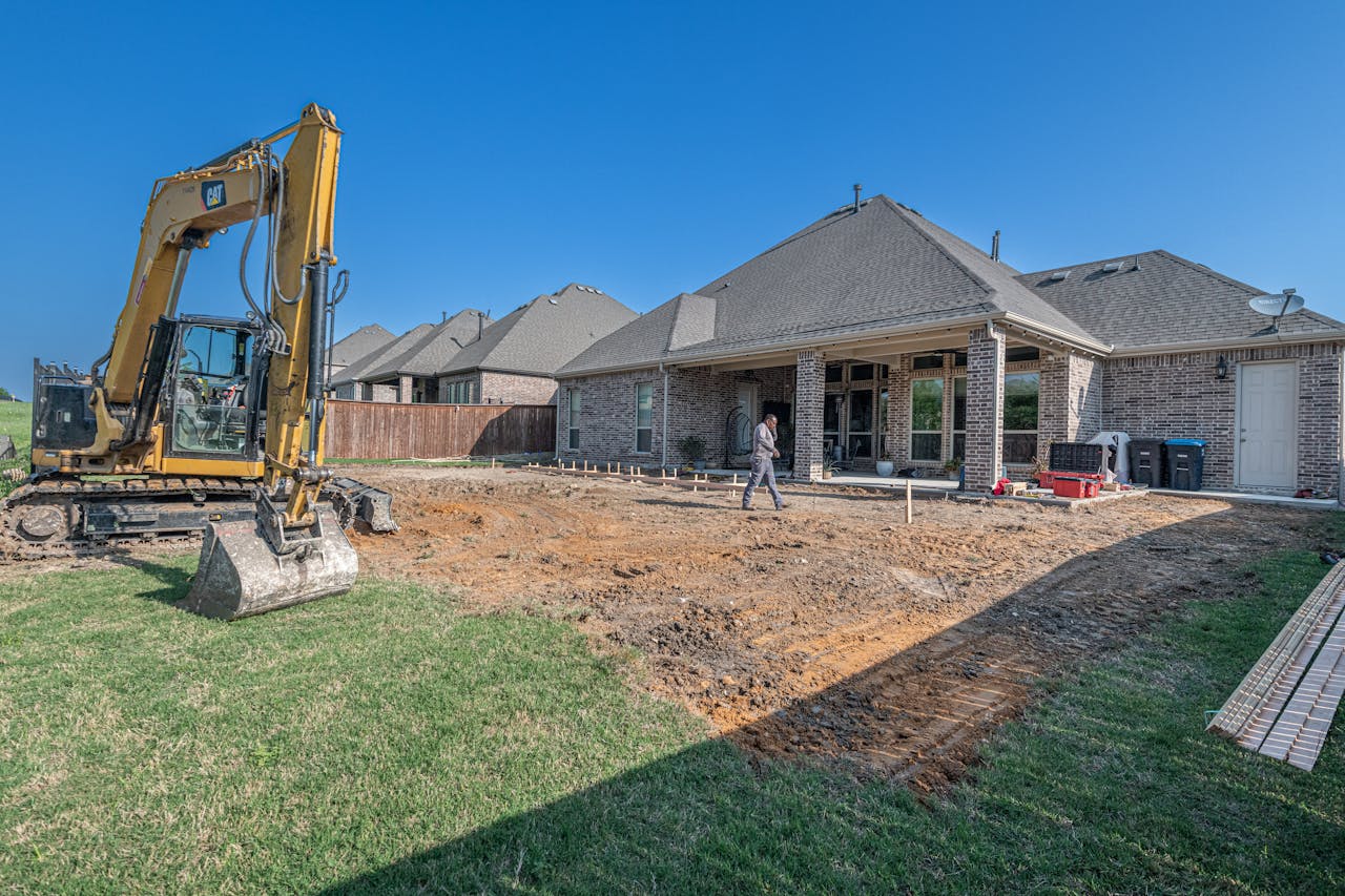 Prestations A construction site for a new patio in a Texas backyard with heavy machinery.